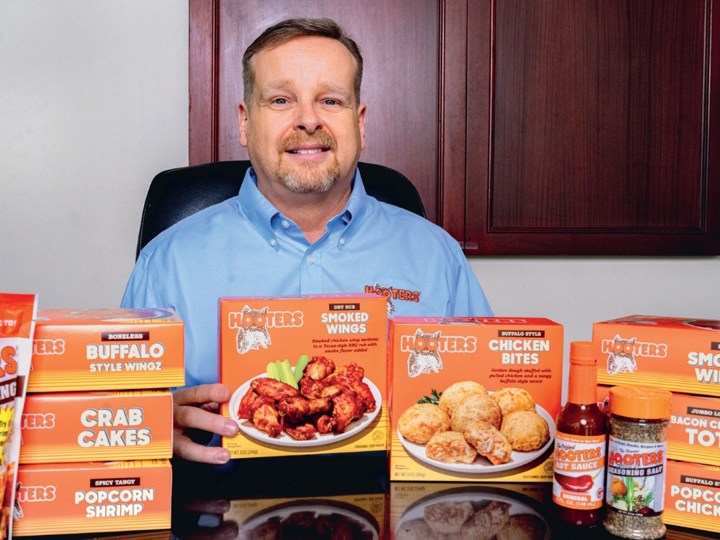 Joel Pounds at a desk with hooters supermarket products